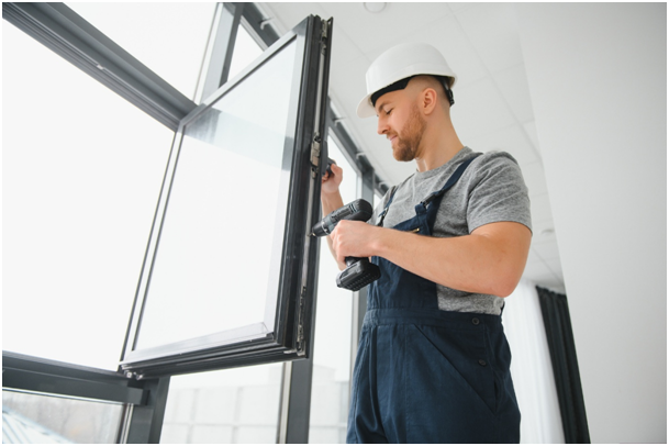 Arbeiter baut Fenster mit Schraubenzieher ein