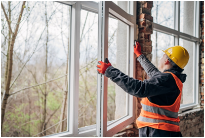 Alt-Attribut: Mann auf Baustelle baut Fenster ein.