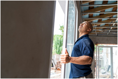 Ein Mann baut ein Fenster auf einer Baustelle ein