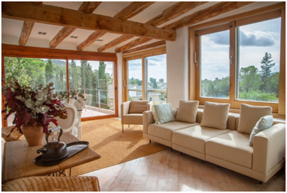 Helles Wohnzimmer mit großen Holzfenstern und Blick ins Grüne