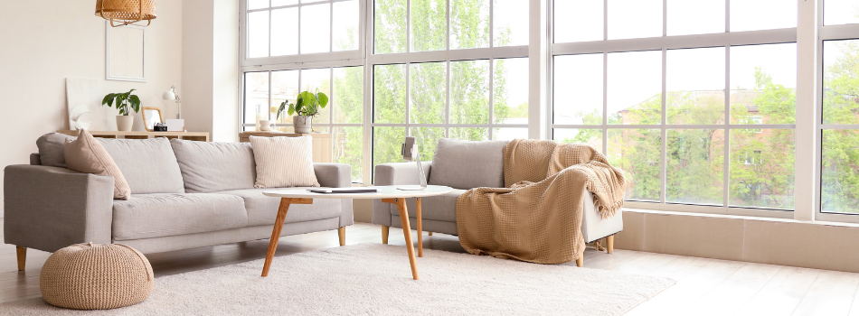 Helles Wohnzimmer mit Sitzecken und Tisch sowie großen Fensterfronten von meinfenster24.
