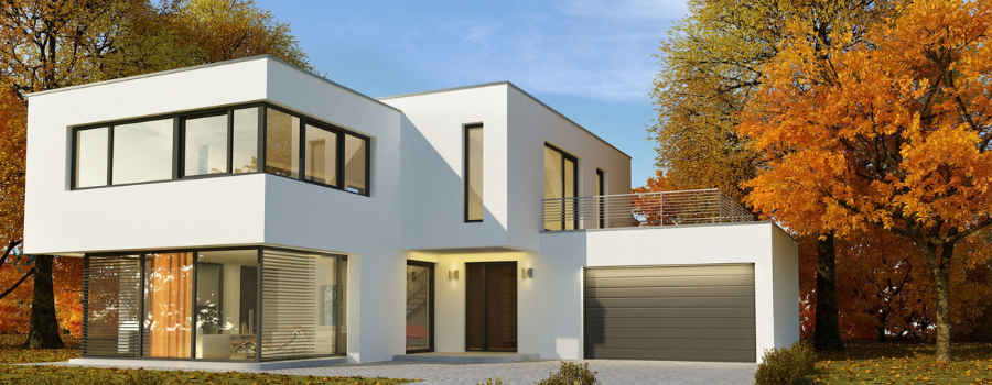 Ein modernes, zweistöckiges Wohnhaus mit großen Fensterfronten und Innenbeleuchtung in einer herbstlichen Umgebung mit anliegender Garage. Diese Bauelemente können nach Maß auf meinfenster24.de konfiguriert werden.